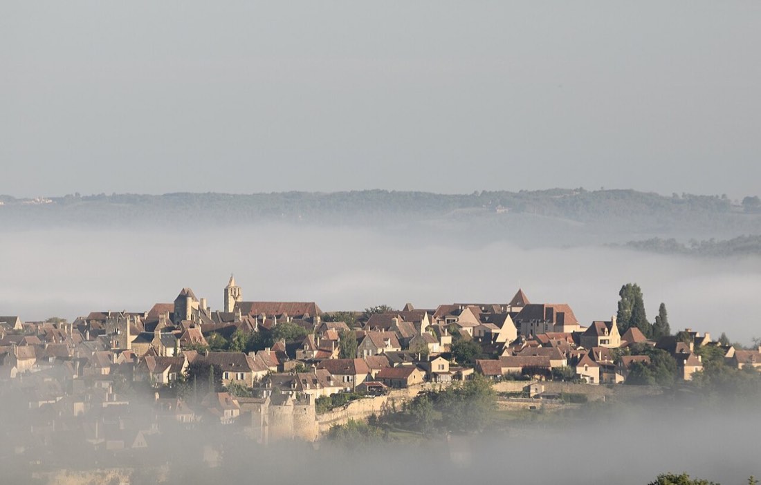 Domme sur sa falaise, au-dessus de la brume